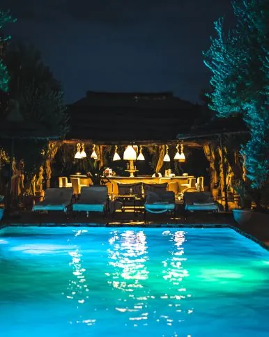 Piscina iluminada de noche junto a una zona chill-out